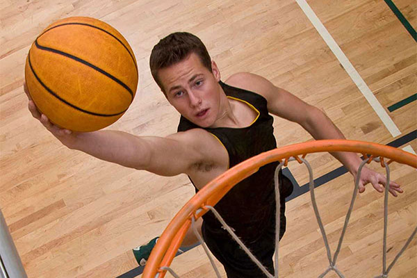 Man runs down the court dribbling a basketball during a game.