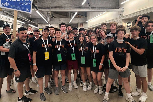 Teens at Maccabi wearing orange shirts with hands together as a team